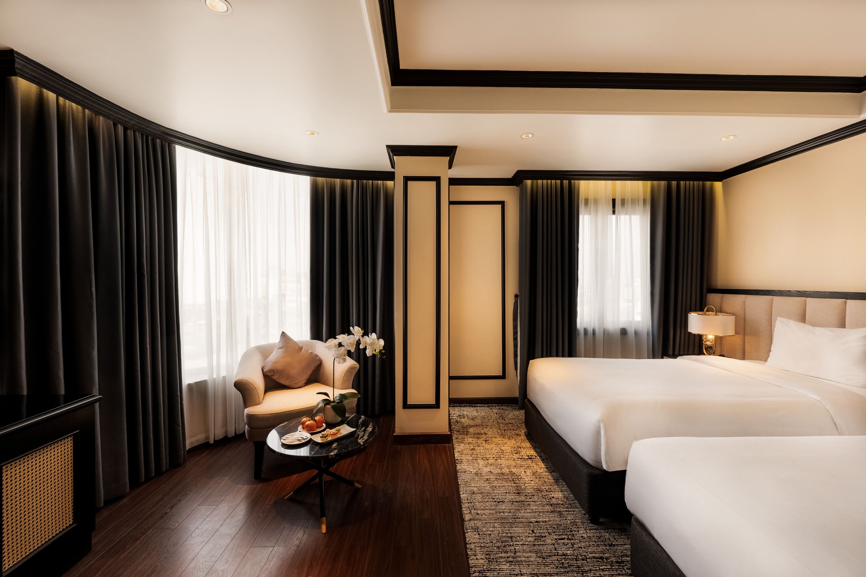 A hotel room with a large bed, a sofa, a coffee table, and a view of the outdoors.