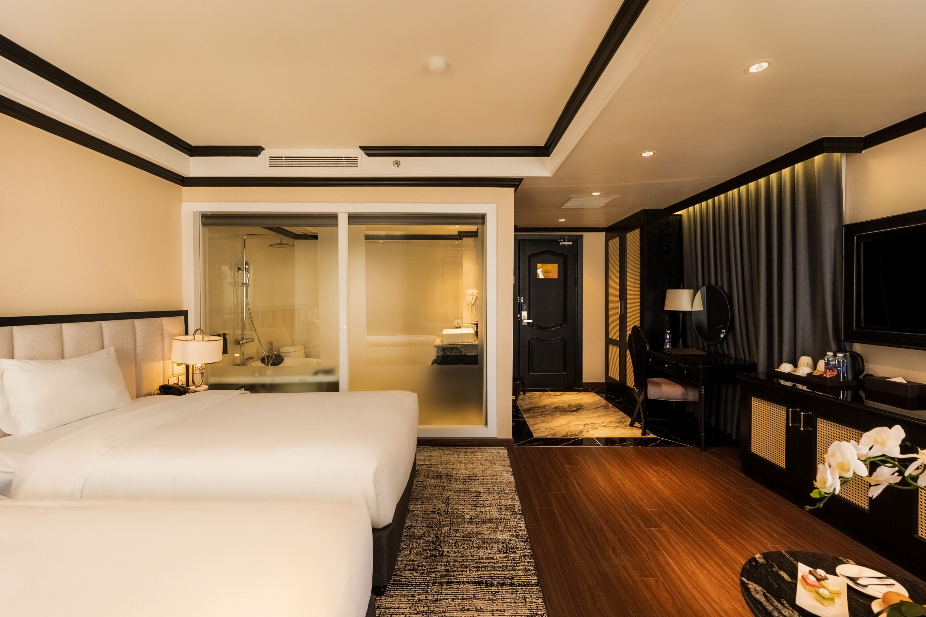 A hotel room with a large bed, a walk-in closet, a desk with a chair, a TV, and a bathroom with a shower and toilet.