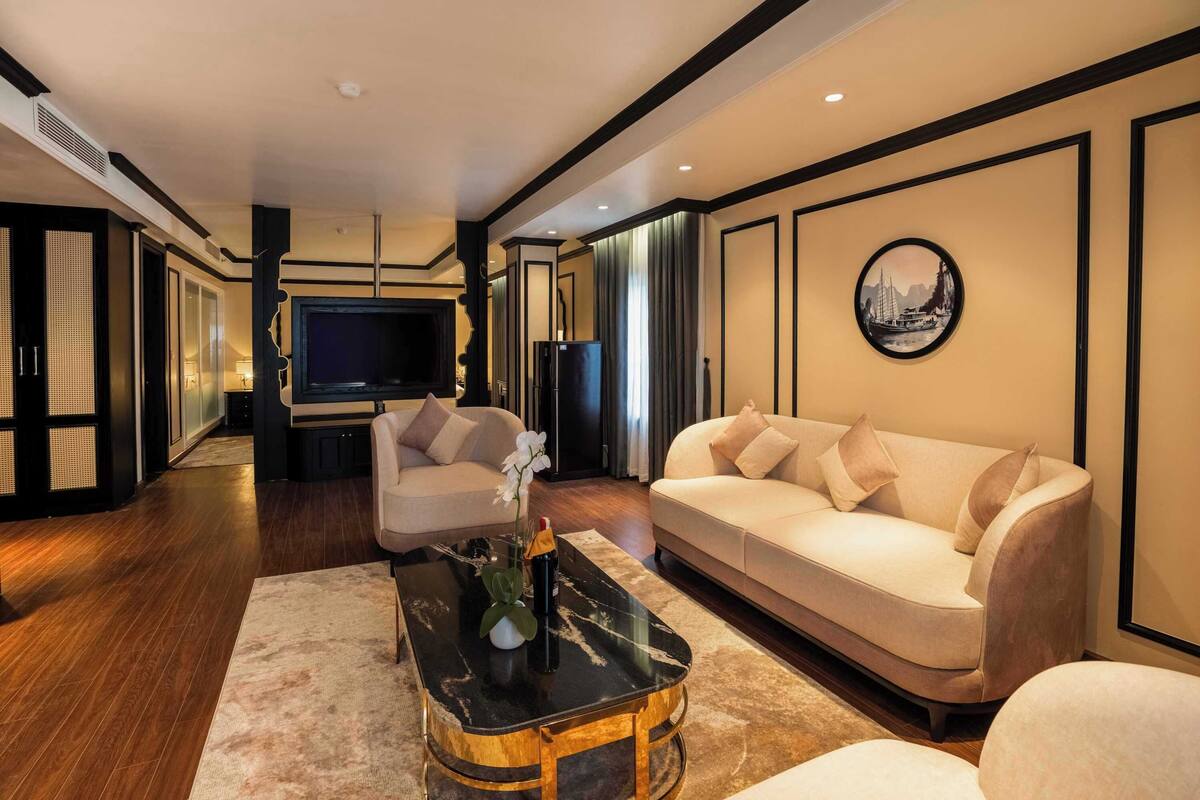 A modern living room with a beige sofa, a black coffee table, and a television in the background.