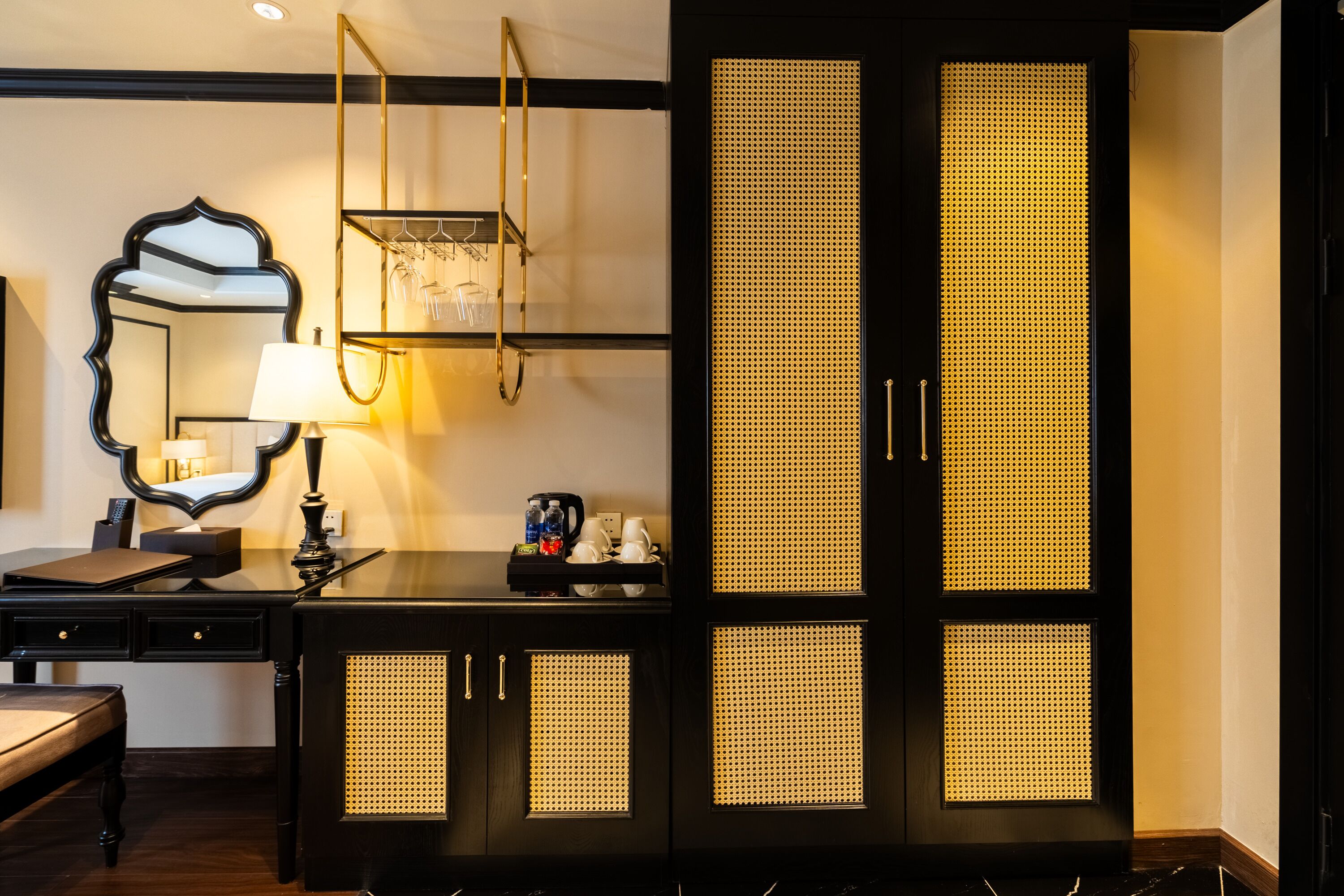 A room with a dark wooden desk, a mirror, a lamp, and a wardrobe with illuminated panels.