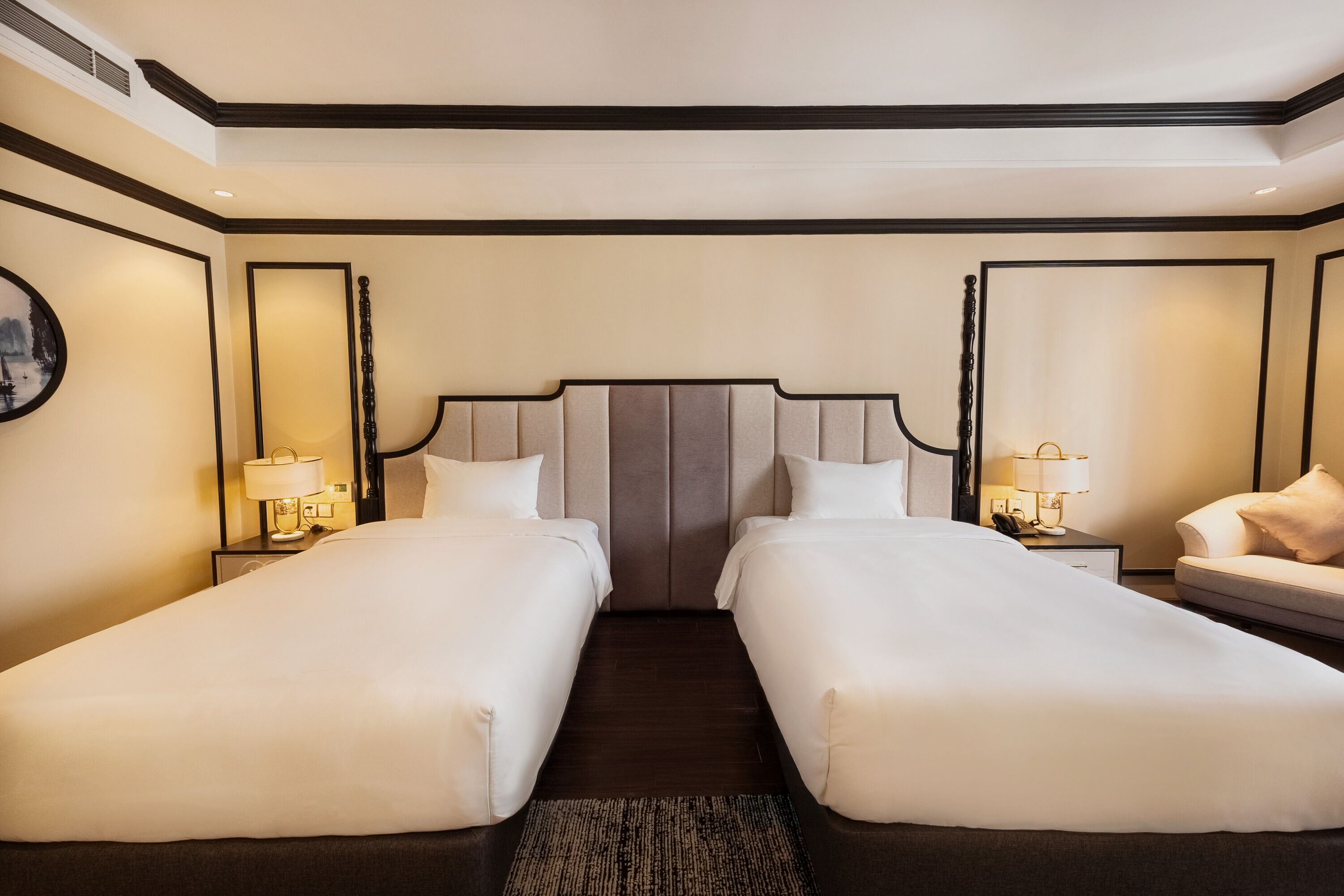 A hotel room with two single beds, a large mirror, and a small sofa.