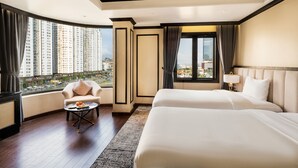 A hotel room with a large bed, a chair, a small table with fruit, and a view of high-rise buildings. - FTE Ha Long Hotel (Bai Chay)