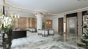 A modern lobby with a reception desk, seating area, and a large column. - FTE Ha Long Hotel (Bai Chay)