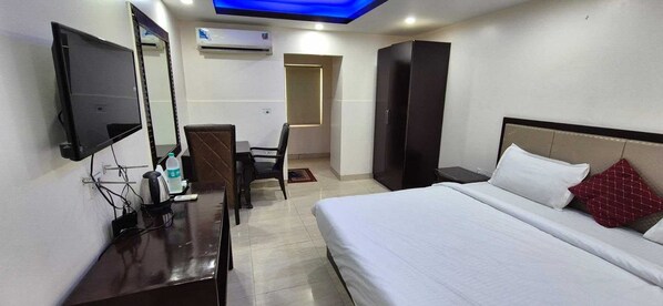 Hotelkamer met een bed, een bureau met een computer, een stoel, een kledingkast en een televisie.