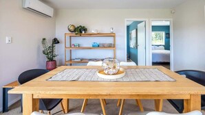 Un comedor moderno con una mesa de madera, dos sillas, un centro de mesa con un cuenco de vidrio y un estante con adornos.