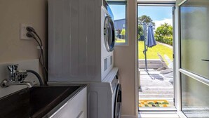 Un área de lavandería con lavadoras apiladas y un lavabo.