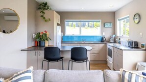 Una cocina compacta con una isla central, dos sillas negras y un ventanal grande.