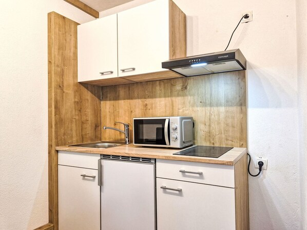 A compact kitchen with a microwave, sink, and wooden cabinetry. - Apart Michelle by Interhome (Huben)