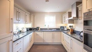 A modern kitchen with white cabinets, granite countertops, stainless steel appliances, and a window with blinds.