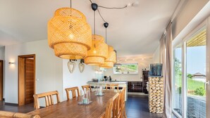 A modern kitchen with a central island, wooden dining table, and chairs. - Simonhöhe Kärntentraum EG by Interhome (Sankt Urban)