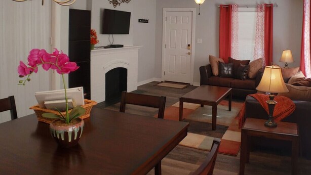 Uma sala de estar com lareira, um sofá, uma mesa de centro e uma mesa de jantar com cadeiras.