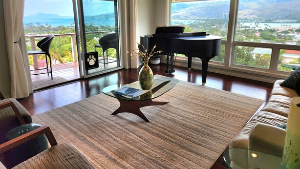 A spacious living room with a piano, a view of the outdoors, and a large window. - Amazing views! Exclusive & peaceful Hawaii Kai. Walk to ocean & hikes, Pool, AC, (Honolulu)