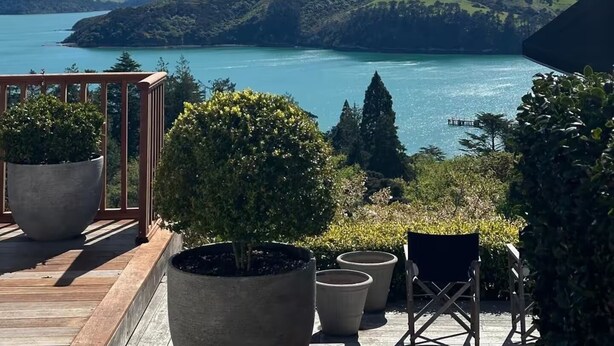 En balkon med plantekasser, udsigt til en sø og fjerne bjerge.