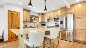 Een moderne keuken met houten kastjes, roestvrijstalen apparatuur en een centraal kookeiland met barkrukken.