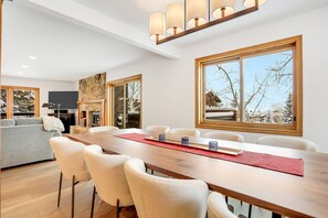 Enjoy meals with family and friends in this spacious dining area, surrounded by large windows and a cozy seating area with a fireplace.