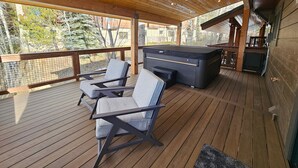 Een houten terras met twee loungestoelen en een whirlpool.