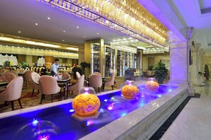 Un lobby de hotel lujoso con una fuente central, asientos elegantes y una zona de bar.