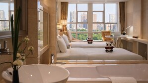 A modern hotel room with a large bed, a sitting area, a desk, and a view of the cityscape. - Sofis Jinyuan Hotel (Chengdu)