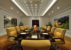 A conference room with a long table, yellow chairs, and paintings on the walls.
