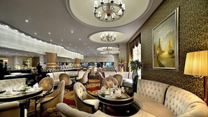 A luxurious hotel lobby with round tables, plush seating, chandeliers, and a large painting on the wall. - Sofis Jinyuan Hotel (Chengdu)