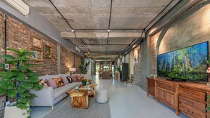 Ein modernes Wohnzimmer mit Backsteinwand, großem Flachbildfernseher, Couchtisch aus Holz und einer Couch.