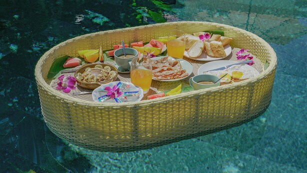 Ein Korbkorb mit Speisen und Getränken schwimmt auf einem Pool.