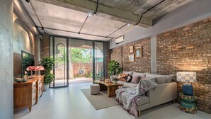 Ein modernes Wohnzimmer mit Backsteinwand, einer Couch, einem Couchtisch und einem Holzkasten.