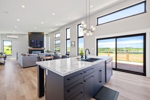 A modern kitchen with a large island, built-in appliances, and a view of the outdoors. - The Heron's Nest - Minutes to Golf & Beaches (New Glasgow)