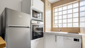 Une cuisine compacte équipée d’un réfrigérateur, d’un four, d’un four à micro-ondes et d’un lave-vaisselle intégrés.