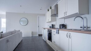 A modern kitchen with white cabinets, a built-in oven, and a sink. - Ridgeway Retreat - 1 Bedroom Cottage - Manorbier (Tenby)