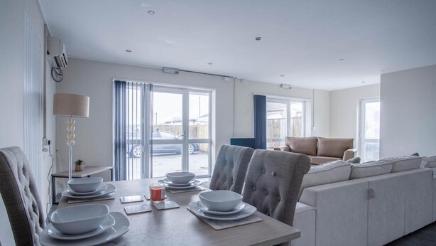 A modern kitchen with a dining table set for four, a sofa, and a view of the outside. - Ridgeway Retreat - 1 Bedroom Cottage - Manorbier (Tenby)