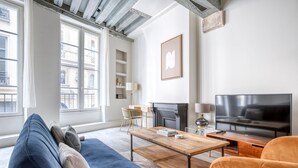 Una sala de estar moderna con un sofá, una mesa de centro, televisión y chimenea.
