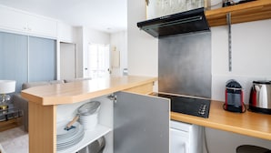 Une cuisine compacte dotée d’un plan de travail en bois, d’une cuisinière intégrée et d’une machine à café.