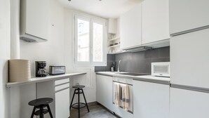 Eine moderne Küche mit weißen Schränken, einer Mikrowelle, einer Kaffeemaschine und zwei Barhocker.