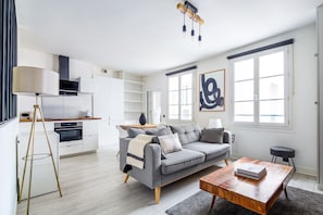 A modern living room with a grey sofa, wooden coffee table, and a floor lamp. - Blueground | Odeon, nr Notre Dame & Seine (Paris)