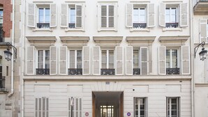 Un bâtiment à la façade symétrique, doté de nombreuses fenêtres avec volets et d’une entrée centrale avec une porte.