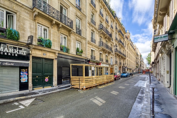 A street with a building featuring a closed shutter on the left and a wooden structure on the right. - Blueground | Saint Philippe du Roule, nr palace (Paris)