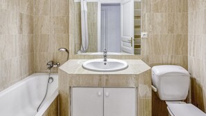 Une salle de bain avec une baignoire, un lavabo, des toilettes et un miroir.