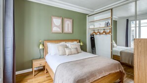 Une chambre à coucher avec un lit en bois, une table de chevet, une armoire et un grand miroir.