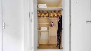 A walk-in closet with shelves, hanging space, and a folded towel rack. - Blueground | Trocadero, intercom, nr Passy Plaza (Paris)
