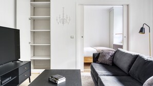 A modern living room with a black TV stand, a grey sofa, and a bookshelf. - Blueground | Trocadero, intercom, nr Passy Plaza (Paris)