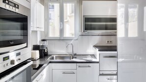 A modern kitchen with stainless steel appliances, a double sink, and white cabinetry. - Blueground | Arc de Triomphe, furnished, elevator (Paris)
