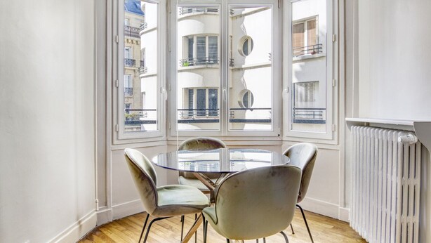 A corner room with a bay window, a round table, and four chairs. - Blueground | Arc de Triomphe, furnished, elevator (Paris)