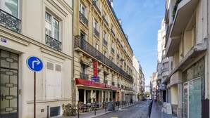 A narrow cobblestone street lined with buildings, a pizza restaurant, and outdoor seating. - Blueground | Arc de Triomphe, furnished, elevator (Paris)