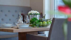 A dining area with a wooden table, a grey upholstered bench, a grey chair, and a pendant light.