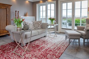 A living room with a sofa, two chairs, a coffee table, and a red patterned rug. - Sönshörn 16 - Morsum - Sönshörn 16, close to the mudflats (Munkmarsch)