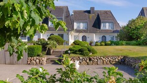 A two-story house with a stone wall and a well-maintained garden.