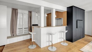Eine moderne Küche mit einer zentralen Kochinsel, Holzschränken und einem schwarzen Kühlschrank.