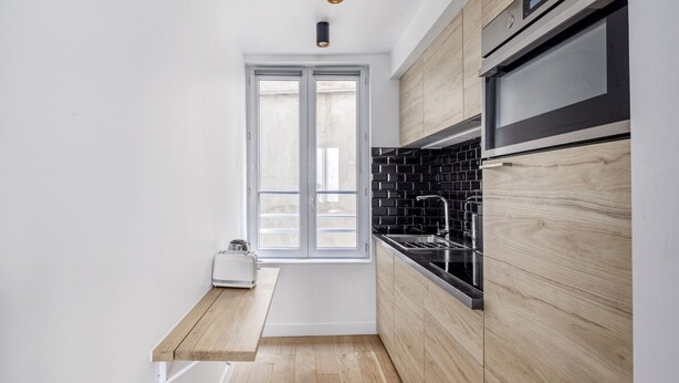A compact kitchen with a window, a built-in oven, and a toaster on a wooden countertop. - Blueground | Latin Quarter, nr Sorbonne (Paris)