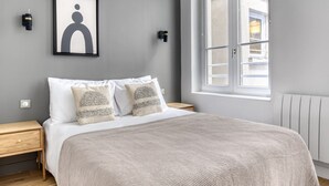 A bedroom with a bed, two bedside tables, a window, and a framed picture on the wall. - Blueground | Latin Quarter, nr Sorbonne (Paris)